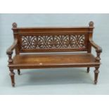 A VICTORIAN OAK SETTLE, THE BACK PIERCED WITH ANTHEMION MOTIFS, THE FOLIATE CARVED HANDLES TO THE