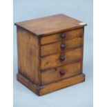 A STAINED PINE COLLECTORS CHEST OF FOUR GRADED DRAWERS ON PLINTH FOOT. H 32cms.