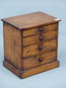 A STAINED PINE COLLECTORS CHEST OF FOUR GRADED DRAWERS ON PLINTH FOOT. H 32cms.