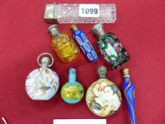 A COLLECTION OF SIX GLASS AND TWO PORCELAIN SCENT BOTTLES, SOME WITH WHITE METAL COVERS, ONE