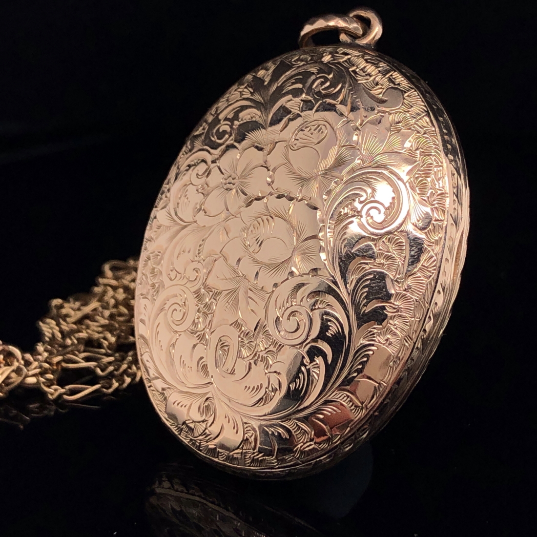 A 9ct GOLD SCROLL ENGRAVED OVAL LOCKET SUSPENDED ON A 9ct GOLD FIGARO STYLE CHAIN. LOCKET