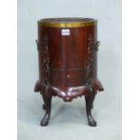AN ANTIQUE MAHOGANY KETTLE STAND WITH METAL LINER, THE CYLINDRICAL BODY CARVED WITH FOLIAGE RELIEFS
