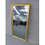 AN ANTIQUE GILT BEVELLED GLASS RECTANGULAR MIRROR WITHIN A GILT FRAME WITH BEADED BAND.