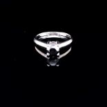 A 9ct WHITE GOLD AND BLACK DIAMOND SOLITAIRE RING. THE ROUND BRILLIANT CUT DIAMOND IN A FOUR CLAW