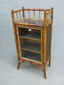 AN EDWARDIAN BAMBOO AND LACQUER GLAZED CUPBOARD, THE DOOR ENCLOSING THREE SHELVES.