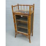 AN EDWARDIAN BAMBOO AND LACQUER GLAZED CUPBOARD, THE DOOR ENCLOSING THREE SHELVES.