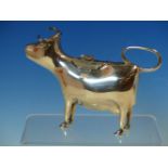 A SILVER HALLMARKED COW FORM CREAMER, THE BODY OF THE COW WITH A HINGED FLORAL COVER AND RESTING