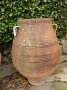 A TERRACOTTA ROMAN URN WITH THREE LUG HANDLES TO THE BELLIED SHAPE, THE RIM. Dia. 49 x H 106cms.