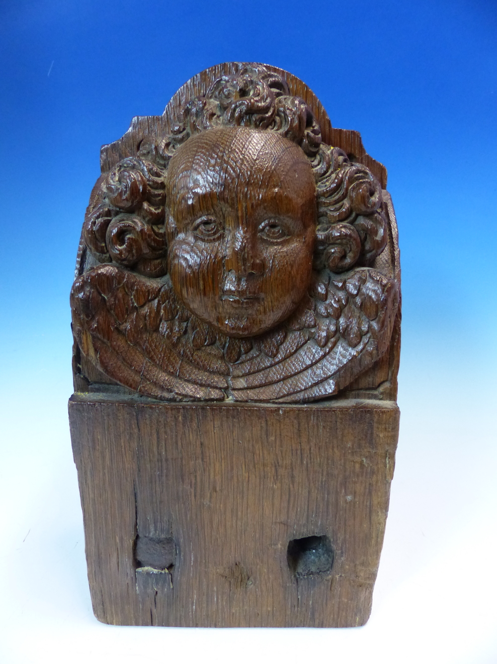 A 17th C. OAK BEAM END CARVED WITH THE HEAD OF A CURLY HAIRED ANGEL. W 15 x D 9 x H 28.5cms.