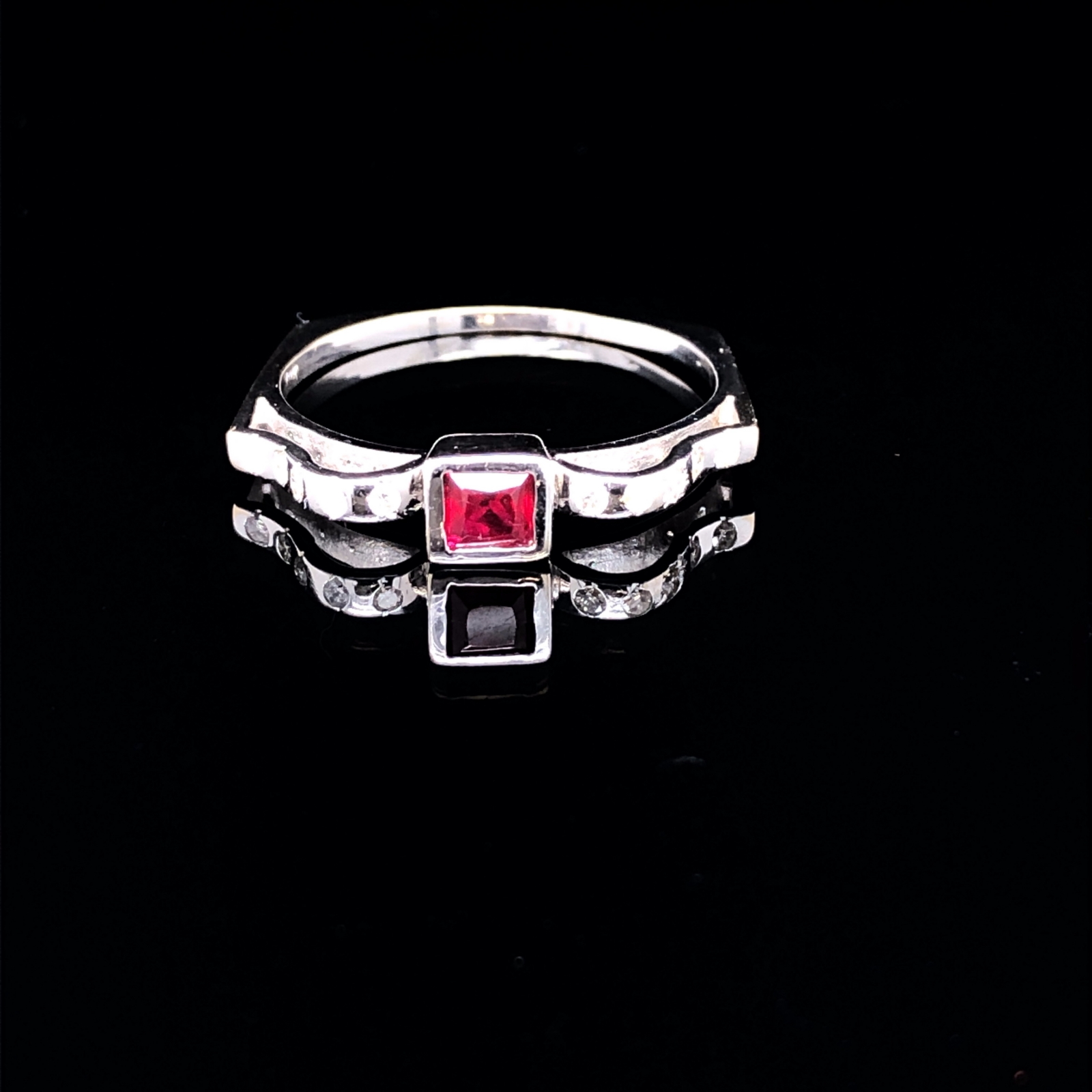 AN 18ct WHITE GOLD UNHALLMARKED RUBY AND DIAMOND RING. THE CENTRAL RUBY PRINCESS CUT IN A RUBOVER - Image 2 of 5