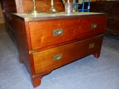 A GREEN LEATHER TOPPED TEAK TWO DRAWER CAMPAIGN CHEST, THE INSET BRASS HANDLES ABOVE BRACKET FEET.