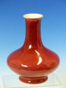 A CHINESE COPPER RED BOTTLE VASE, THE SLENDER NECK ABOVE A COMPRESSED SPHERICAL BODY, SIX