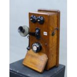 A STROMBERG CARLSEN WALL MOUNTING OAK CASED TELEPHONE WITH BLACK PLASTIC EAR PIECE AND MICROPHONE