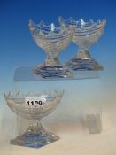 A SET OF THREE CUT GLASS NAVETTE SALTS, POSSIBLY IRISH, THE TREFOIL RIMS ABOVE SWAG CUT BODIES ON