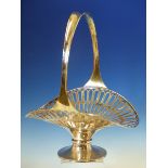 A LARGE AND UNUSUAL FLOWER BASKET FORM FRUIT BASKET WITH HIGH HOOP HANDLE AND PIERCED EDGE RIM ON