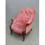 AN EARLY VICTORIAN BUTTON BACK ARMCHAIR WITH CARVED SHOW FRAME ARMS ON TURNED FORELEGS WITH BRASS