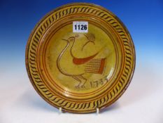 A SLIPWARE BRICK RED POTTERY DISH, THE STRAW COLOURED OVERLAY SGRAFFITO DECORATED WITH A DOVE AND