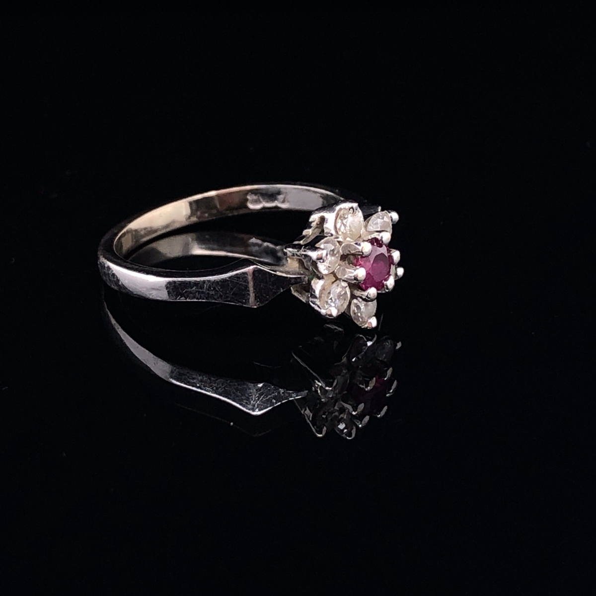 AN 18ct WHITE GOLD RUBY AND DIAMOND CLUSTER RING. THE RUBY A ROUND CUT IN A SIX CLAW SETTING