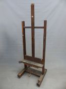 A VINTAGE OAK EASEL, THE PICTURE RESTING CRANKING UP AND DOWN ON A WOODEN SCREW AND WITH FOLD OUT