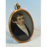 A GEORGIAN OVAL MINIATURE OF A GENTLEMAN IN YELLOW METAL MOUNT, INSET LOCK OF HAIR VERSO. 6.5 x