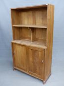 AN ARTS AND CRAFTS STYLE OAK BOOKCASE CABINET IN THE MANNER OF PETER WAALS, WITH SLIDING DOORS TO