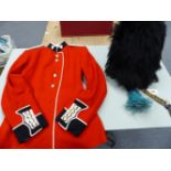 AN IRISH GUARDS REGIMENTAL TUNIC TOGETHER WITH A BUSBY WITH A BLUE PLUME TO ONE SIDE AND BRASS CHAIN
