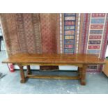 AN OAK REFECTORY TABLE, THE CLEATED THREE PLANK RECTANGULAR TOP ABOVE AN APRON JOINED BY BRACKETS TO