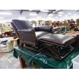 A LATE VICTORIAN DARK LEATHER ADJUSTABLE ARM CHAIR WITH SLIDE UNDER FOOT REST, THE ARMS HINGED AT