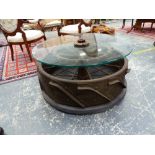 A GLASS TOPPED INDUSTRIAL IRON COFFEE TABLE, THE SPOKED WHEEL BASE WITH APPLIED BLADE TREAD. Dia. 42