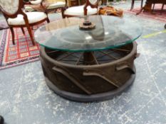 A GLASS TOPPED INDUSTRIAL IRON COFFEE TABLE, THE SPOKED WHEEL BASE WITH APPLIED BLADE TREAD. Dia. 42