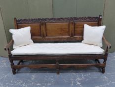 AN 18th C. OAK SETTLE, THE SCROLLING FOLIAGE CARVED TOP RAIL OVER THREE PANEL BACK, THE SEAT ONCE