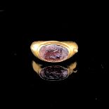 A ROMAN GOLD RING INSET WITH A CRUDELY CARVED GLASS SEAL THOUGHT BE A PALMETTE MOTIF. CIRCA 1st C.