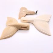 THREE WOOLY MAMMOTH IVORY PENDANTS, EACH CARVED AS BICUSPID FISH TAILS, THE LARGEST. H 5cms.