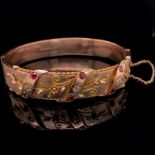 AN EDWARDIAN ANTIQUE 9ct OLD GOLD RUBY AND DIAMOND BANGLE, DATED 1910 FOR BIRMINGHAM. THE FRONT WITH