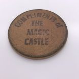 A WOODEN ROUNDEL INSCRIBED IN BLACK ON ONE SIDE COMPLIMENTS OF THE MAGIC CASTLE AND ON THE OTHER