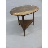 AN ANTIQUE OAK CRICKET TABLE ON SHAPED SQUARE LEGS WITH PLATFORM UNDER-TIER. 68cm (DIA) x 69cm (H).