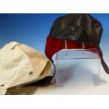 A BLACK LEATHER AND A WHITE CLOTH DRIVING HOOD, THE FORMER WITH QUILTED RED SILK LINING, THE