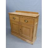 AN ANTIQUE PINE SIDE CABINET WITH TWO DRAWERS OVER DOORS ENCLOSING SHELVES ABOVE THE PLINTH FOOT. W