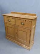 AN ANTIQUE PINE SIDE CABINET WITH TWO DRAWERS OVER DOORS ENCLOSING SHELVES ABOVE THE PLINTH FOOT. W