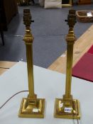 A PAIR OF GILT METAL SQUARE COLUMN TABLE LAMPS FLUTED BETWEEN THE BEADED TOPS AND FEET. H 48.5cms.