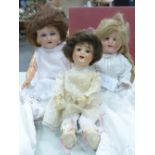 THREE BISQUE HEADED DOLLS TOGETHER WITH A QUANTITY OF DOLLS CLOTHES, THE TALLEST DOLL BY SIMON AND