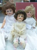 THREE BISQUE HEADED DOLLS TOGETHER WITH A QUANTITY OF DOLLS CLOTHES, THE TALLEST DOLL BY SIMON AND