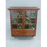 A VICTORIAN OAK WALL CABINET, THE PEDIMENT OVER DOORS GLAZED IN CLEAR AND GREEN BOTTLE END GLASS