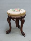 A VICTORIAN ROSEWOOD PIANO STOOL, THE SEAT NEEDLE WORKED WITH FRUIT AND RISING ON A SCREW ABOVE