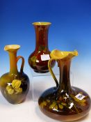 TWO AMERICAN ROOKWOOD EWERS AND A VASE, EACH WITH SLENDER NECKS ABOVE ROUNDED BODIES AND DECORATED