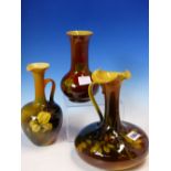 TWO AMERICAN ROOKWOOD EWERS AND A VASE, EACH WITH SLENDER NECKS ABOVE ROUNDED BODIES AND DECORATED