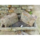 A CARVED STONE SHALLOW SINK ON STONE SUPPORTS. TOGETHER WITH A SMALLER SIMILAR SINK.