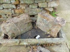 A CARVED STONE SHALLOW SINK ON STONE SUPPORTS. TOGETHER WITH A SMALLER SIMILAR SINK.