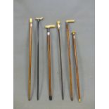 THREE WALKING STICKS AND THREE CANES WITH IVORY HANDLES, ONE CARVED AS A HAND HOLDING A BALL