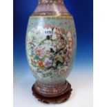 A CHINESE FAMILLE ROSE VASE WITH WOOD STAND, THE BALUSTER SHAPE PAINTED WITH RESERVES OF FLOWERS AND